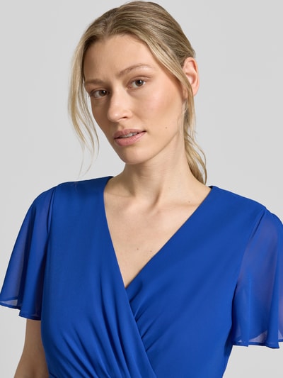 Kobiece modelka nosi 'Knielanges Cocktailkleid mit Bindegürtel' od Christian Berg Cocktail z szyfonu, taliowany fason, kopertowy styl, długość do kolan, wiązany pasek, szerokość w rozmiarze 36: 38 cm, długość tyłu w rozmiarze 36: 111 cm, długość rękawów w rozmiarze 36: 22 cm, intensywny niebieski kolor, gładka tekstura, zbliżenie na górną część ciała
