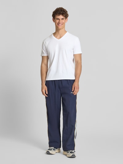 Männermodel trägt T-Shirt aus Baumwoll-Leinen-Mix mit V-Ausschnitt von Superdry, weiß, Regular-Fit, sichtbares Stitching, Rückenlänge 68 cm bei Größe M, Ganzkörperansicht von vorne.