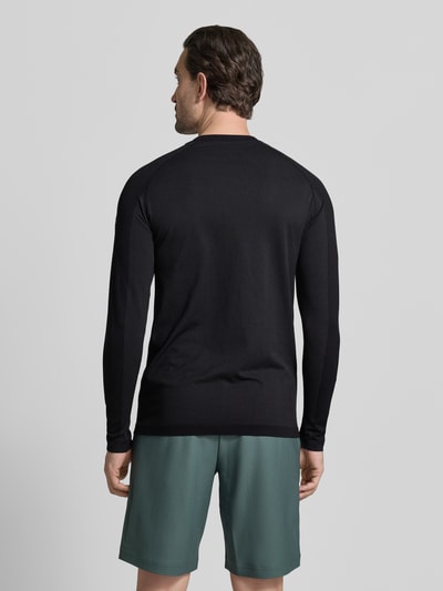 Männermodel trägt Slim Fit Langarmshirt aus atmungsaktivem Material Modell 'TRAINING DAY' van Fabletics, effen zwart, reflecterende logoprint, lichtgewicht stof, vierwegstretch, geurremmend en zweetregulerend, ronde hals, lange mouwen, geheel van achteren.