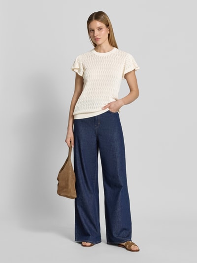 Frauenmodel trägt Strickshirt mit Lochstickerei Modell 'Ganna' von MOS MOSH aus Reine Baumwolle, Gerader-Schnitt, Rundhalsausschnitt, Volantärmel, cremefarben, kombiniert mit blauer weiter Jeans, Ganzkörperansicht von vorne.