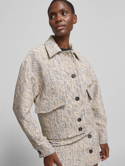 Frauenmodel trägt Regular Fit Jacke mit Viskose-Anteil von Iro in beige-grauem Material-Mix mit Umlegekragen, durchgängiger Knopfleiste und Pattentaschen, Ganzkörperansicht von vorne. Rückenlänge bei Größe 36: 58 cm, Brustweite 51 cm, Ärmellänge 56 cm.