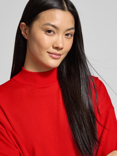 Vrouwenmodel draagt Oversized Strickpullover mit Stehkragen Modell 'MATHISA' van Drykorn in felrood, pure scheerwol, geribde randen, nahaufnahme bovenlichaam.