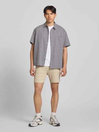 Männermodel trägt Loose Fit Sweatshorts aus Bio-Baumwoll-Mix Modell 'KIAN' von Only & Sons in Beige, Optik: Unifarben, Materialverarbeitung: Piqué, Label-Patch, Bundabschluss: elastisch mit Tunnelzug, seitliche Eingrifftaschen, angedeutete Paspeltaschen, Ganzkörperansicht von vorne.