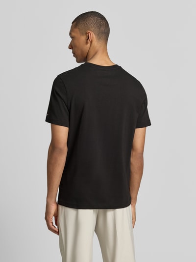 Männermodel trägt Regular Fit T-Shirt aus reiner Baumwolle von Tommy Hilfiger, unifarben schwarz, kurzarm, Rückansicht Ganzkörperansicht.
