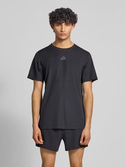 Männermodel trägt Regular Fit Sport T-Shirt mit Label Print von adidas Training, Optik: Unifarben, Ganzkörperansicht von vorne.