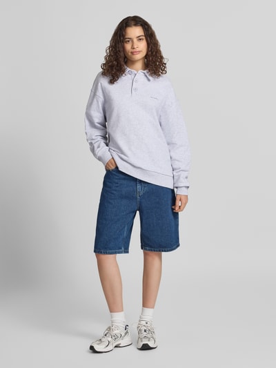 Frauenmodel trägt Oversized Sweatshirt mit Polokragen und Label-Print von OH APRIL in Hellgrau aus reiner Baumwolle, Ganzkörperansicht von vorne.