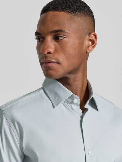 Männermodel trägt Slim Fit Businesshemd aus Stretch-Twill Modell 'P-HANK-KENT-C1-222' von BOSS, Optik: Unifarben, Nahaufnahme Oberkörper.