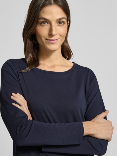 Kobiece modelka nosi Longsleeve aus Baumwolle mit Logo-Detail od MARC O’POLO, granatowy, prosty krój, okrągły dekolt, zbliżenie na górną część ciała.