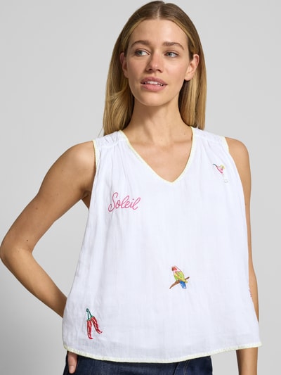 Frauenmodel trägt Blusentop mit Stitchings von Marc Cain aus weißer Baumwolle mit bunten Stickereien, V-Ausschnitt, Nahaufnahme Oberkörper.