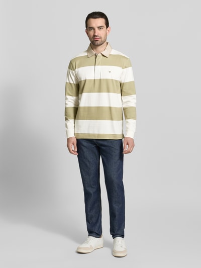 Männermodel trägt Regular Fit Poloshirt mit Streifenmuster und Label-Stitching von Fynch-Hatton, longslve, reine Baumwolle, Ganzkörperansicht von vorne.
