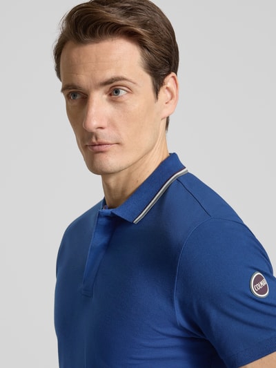 Männermodel trägt Slim Fit Poloshirt aus Baumwolle von Colmar Originals in Blau mit Polokragen und Label-Details, Nahaufnahme Oberkörper.