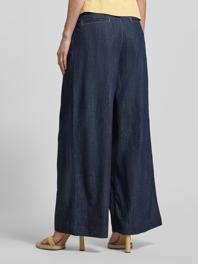 Frauenmodel trägt Jeans mit Gesäßtaschen Modell 'ARTEMIDE' von Mango, Wide Leg, reine Baumwolle, dunkles Blau, Ganzkörperansicht Rückansicht.