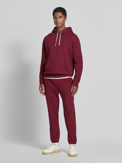Männermodel trägt Relaxed Fit Sweathose aus Baumwoll-Mix von Polo Ralph Lauren in Dunkelrot, weiche Textur, Ganzkörperansicht von vorne. Herren Sweathose von Polo Ralph Lauren