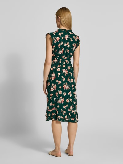 Frauenmodel trägt Kleid aus Viskose mit Bindegürtel und Volantsaum von Apricot, Midikleid mit floralen Mustern, taillierter Schnitt, Ganzkörperansicht Rückansicht. Rückenlänge bei Größe S: 94 cm, Brustweite 51 cm, Ärmellänge 7 cm.