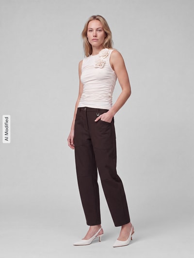Frauenmodel trägt Gerade Hose mit Gürtelschlaufen Modell 'Baggy Smart' von MAC in Dunkelbraun, kombiniert mit hellem Top, Ganzkörperansicht von vorne, KI-modifiziertes Bild. Damen Gerade Hose von MAC.
