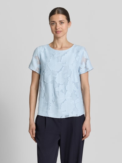 Frauenmodel trägt Blusenshirt aus Viskose-Mix mit Strukturmuster von More & More in Hellblau mit geradem Schnitt und Rundhalsausschnitt, Ganzkörperansicht von vorne.