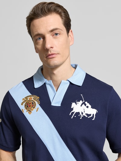 Männermodel trägt Regular Fit Poloshirt aus reiner Baumwolle von Polo Ralph Lauren in Two Tone Navy-Hellblau mit Logo- und Label-Stitching, Nahaufnahme Oberkörper.