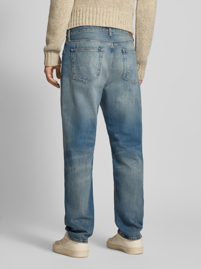Männermodel trägt Tapered Fit Jeans aus reiner Baumwolle Modell 'SONNY' von Tommy Jeans in Denim-Optik und Used-Look, Ganzkörperansicht Rückansicht.