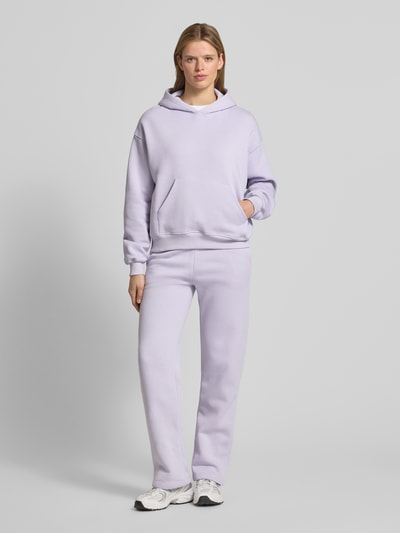 Modelka kobieca nosi Sweatpants mit elastischem Bund Modell 'Iconic' od Gina Tricot, bawełniany miks, krój relaxed fit, elastyczny pas, tunel, długość wewnętrzna nogawki S: 80 cm, lawendowy kolor, pełny widok od przodu