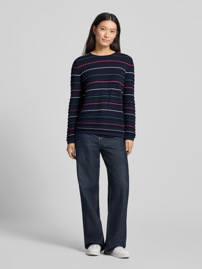Frauenmodel trägt Strickpullover mit Struktur-Muster von Christian Berg Woman in Dunkelblau mit bunten Streifen, Rundhalsausschnitt, reine Baumwolle, gerader Schnitt, kombinierbar mit Jeans und Sneakern, Ganzkörperansicht von vorne.