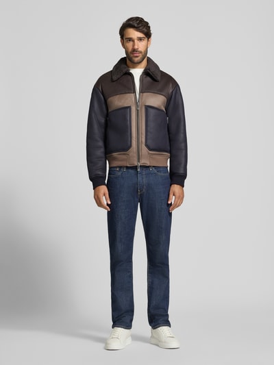 Męski model nosi Blouson in Leder-Optik mit Zweiwege-Reißverschluss von Armani Exchange, Materiał skóropodobny, krój regular fit, wykładany kołnierz z futerka, zamek błyskawiczny dwustronny, widok całej sylwetki z przodu.