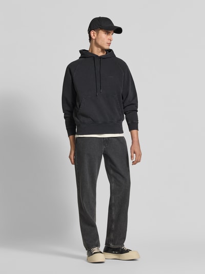 Männermodel trägt Regular Fit Hoodie aus reiner Baumwolle von Closed in Schwarz mit Kapuze und Känguru-Tasche, Ganzkörperansicht von vorne.