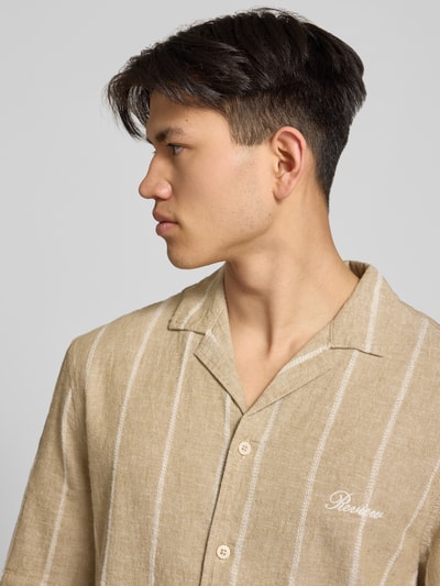 Männermodel trägt Regular Fit Freizeithemd aus Baumwoll-Leinen-Mix mit Reverskragen von REVIEW, beige mit weißen Streifen, Nahaufnahme Oberkörper.