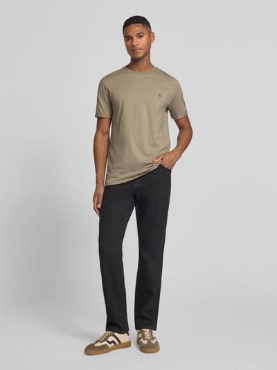 Männermodel trägt T-Shirt mit Logo-Stitching Modell 'Norregaard' von Les Deux in Beige, aus Baumwolle, gerader Schnitt, Ganzkörperansicht von vorne.