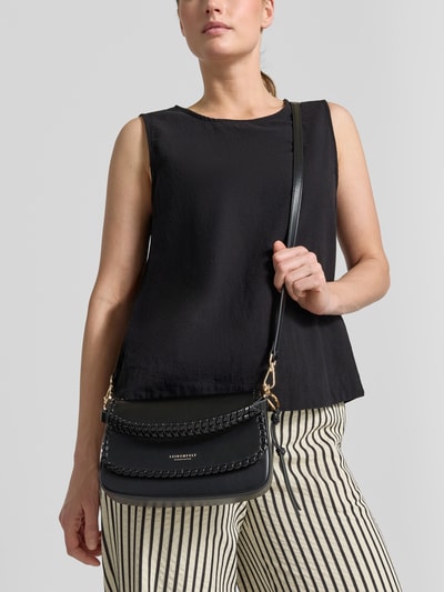 Vrouwenmodel draagt zwarte Handtasche mit Label-Detail Modell 'LILJENDAL' van Seidenfelt, zwart, met labeldetail, hoofdvak met omslag, magneetsluiting, lang hengsel, verstelbare schouderband, breedte 21 cm, lengte 15 cm, diepte 5 cm, bandlengte 133 cm, detailopname bovenlichaam.