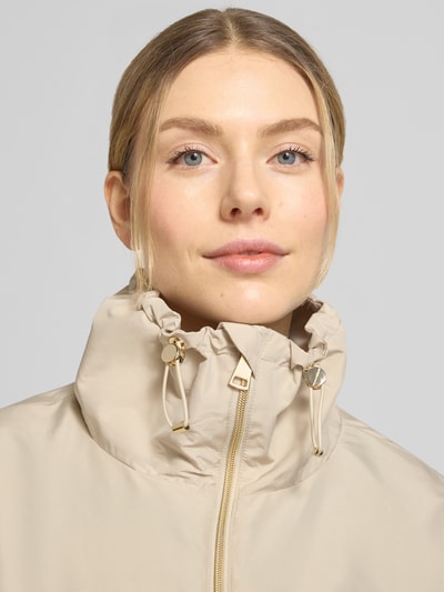 Vrouwenmodel draagt Jacke mit Zweiwege-Reißverschluss van WHITE LABEL in regular fit, lichtbeige kleur, staande kraag, close-up bovenlichaam.