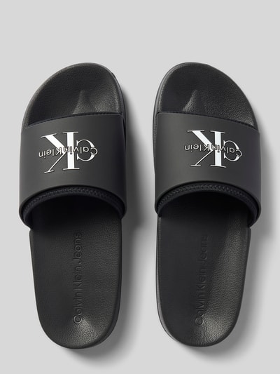 Produktfoto, czarne Badeschuhe mit Label-Prägung od CK Calvin Klein z białym logo, matowa faktura, widok z góry