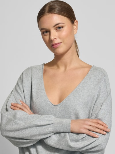 Frauenmodel trägt Strickpullover aus Baumwoll-Kaschmir-Mix Modell 'RISORY' von Drykorn in Hellgrau, Relaxed-Fit, V-Ausschnitt, Nahaufnahme Oberkörper. Damen Strickpullover, Rückenlänge bei Größe S: 53 cm, Ärmellänge bei Größe S: 48 cm.