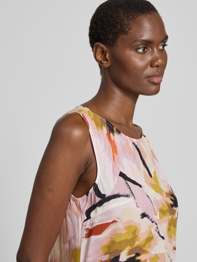 Modelka kobieca nosi Fließendes Kleid aus Baumwoll-Mix od Tom Tailor z wzorem allover w pastelowych kolorach, materiał bawełniany mix, krój luźny, długość do kolan, dekolt okrągły, bez rękawów, zbliżenie na górną część ciała, widok z przodu.