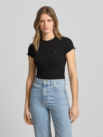 Modelka prezentuje damski t-shirt Slim Fit T-Shirt aus Baumwoll-Mix od Tommy Hilfiger, czarny, okrągły dekolt, detal z logo, drobne prążkowanie, zakończenia frill, mieszanka bawełny, Ganzkörperansicht von vorne.