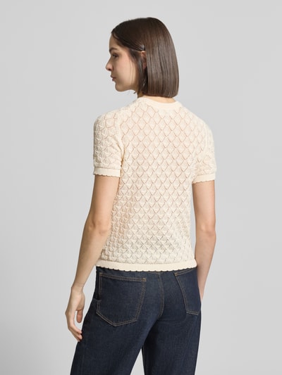Modelka kobieca nosi Strickshirt mit Lochstickerei von Jake*s Collection z mieszanki bawełny, prosty krój, kremowy kolor, półrękaw, widoczne tekstury ażuru, widok całej sylwetki od tyłu.