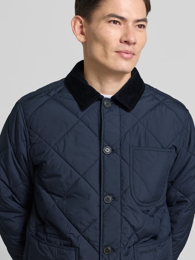 Männermodel trägt Regular Fit Steppjacke mit Kentkragen von Polo Ralph Lauren, Dunkelblau, Knopfleiste, Brusttasche, Label-Stitching, Nahaufnahme Oberkörper.