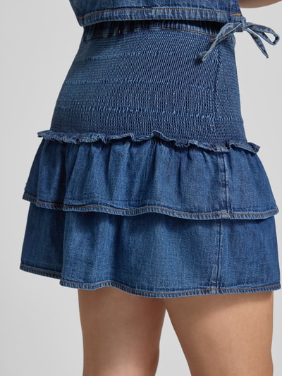 Frauenmodel trägt Denim Minirock aus reiner Baumwolle mit Volants von Tommy Jeans in blauer Denim-Optik und Crinkle, Detailaufnahme