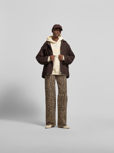 Frauenmodel trägt Oversized Hoodie aus reiner Baumwolle von Anine Bing in Creme mit Känguru-Tasche, Label-Detail, elastische Abschlüsse, Rückenlänge 63 cm bei Größe S, Ganzkörperansicht von vorne.