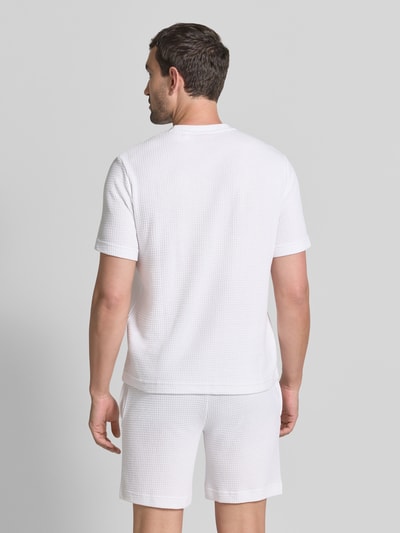 Męski model nosi Męski t-shirt z mieszanki bawełny model 'AUSTIN' od HUGO w kolorze białym, tekstura w drobne kratki, widok całej sylwetki z tyłu.