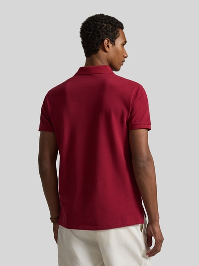 Männermodel trägt Regular Fit Poloshirt aus reiner Baumwolle von Polo Ralph Lauren, unifarben, Piqué-Textur, Ganzkörperansicht Rückansicht.