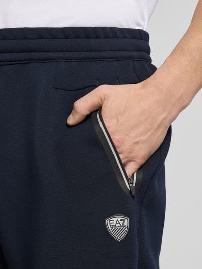 Männermodel trägt Shorts mit elastischem Bund von EA7 Emporio Armani in Dunkelblau, Material-Mix, Nahaufnahme Hüfte und Hand