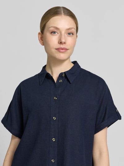 Frauenmodel trägt Relaxed Fit Bluse aus Leinen-Viskose-Mix Modell 'Lava' von FREE/QUENT in Dunkelblau, Nahaufnahme Oberkörper. Bluse mit Hemdblusenkragen, kurzer Knopfleiste und kurzen Ärmeln, glatte Textur, Rückenlänge 55 cm, Ärmellänge 12 cm.