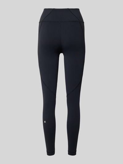 Frauenmodel trägt schwarze Leggings mit Stretch-Anteil Modell 'SHKOUT' von Salomon mit Elastischer-Material-Mix und Label-Print, Ganzkörperansicht Rückansicht.