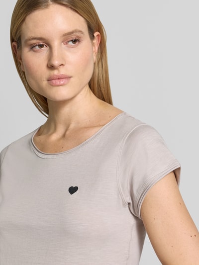 Frauenmodel trägt T-Shirt mit Stitching und Rundhalsausschnitt von Christian Berg Woman aus reiner Baumwolle, helles Beige, Nahaufnahme Oberkörper.