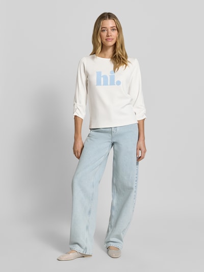 Vrouwenmodel draagt Sweatshirt mit 3/4-Arm van More & More, wit met lichtblauwe print, modalmix met stretch, regular fit, ronde hals, 3/4-mouw, lichte denimbroek, lichte achtergrond, ganzkörperansicht van voren