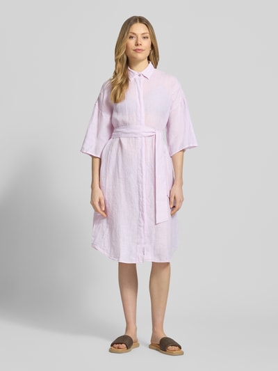 Frauenmodel trägt Leinenkleid aus reinen Leinen Modell 'Derby' von 0039 Italy, taliowany krój, rękaw o dł. 1/2, wykładany kołnierz, listwa guzikowa, półprzezroczysty materiał, odpinana materiałowa tasiemka, długość tyłu w rozmiarze S: 96 cm, szerokość w rozmiarze S: 59 cm, długość rękawów w rozmiarze S: 24 cm, jasnoróżowy, prosty krój, widoczna tekstura lnu, Ganzkörperansicht von vorne.