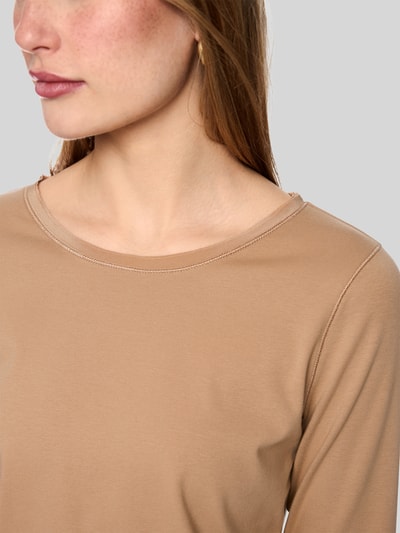 Frauenmodel trägt Slim Fit Langarmshirt aus Baumwoll-Mix von Marc Cain in Beige mit U-Boot-Ausschnitt, Nahaufnahme Oberkörper. Damen Langarmshirt, elastischer Baumwoll-Mix, Logo-Stickerei, Rückenlänge bei Größe 36: 58 cm.
