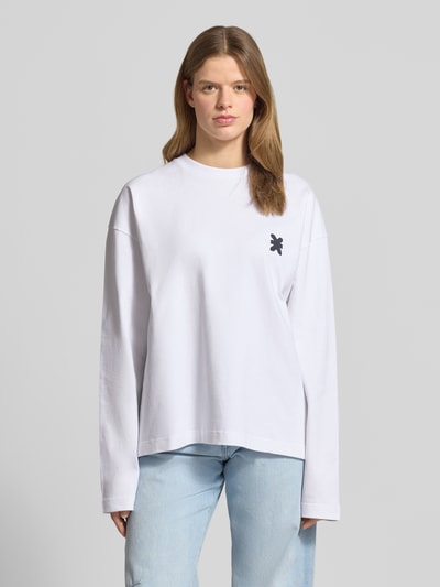 Kobiece modelka nosi Oversized Longsleeve mit rückseitigem Statement-Print von Karo Kauer, bawełna, krój oversized fit, okrągły dekolt, nadruk z logo, przód w jasnym kolorze, gładka faktura, Ganzkörperansicht von vorne.