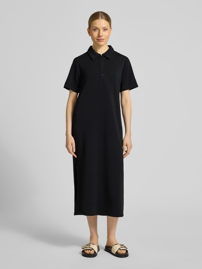 Frauenmodel trägt schwarzes Polokleid mit Knopfleiste Modell 'Helle' von My Essential Wardrobe, Material-Mix, gerader Schnitt, Ganzkörperansicht von vorne.