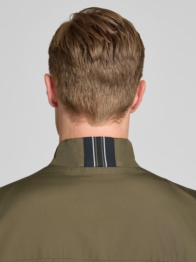 Männermodel trägt Blouson mit Stehkragen und Reißverschluss von Geox in Olivgrün, glatte Struktur, Detailaufnahme Rückenansicht. Regular-Fit, Eingrifftaschen, Rückenlänge bei Größe M: 68 cm, Schulterbreite: 46 cm, Brustweite: 56 cm, Ärmellänge: 68 cm.